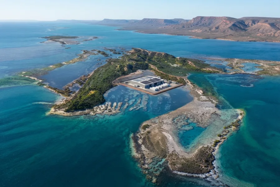 Aerial overview of a remote Australian coastal industrial facility powered by an integrated microgrid system featuring large-scale solar PV arrays, battery energy storage containers, and backup generation with 500kWh-100MWh+ scalable energy capacity